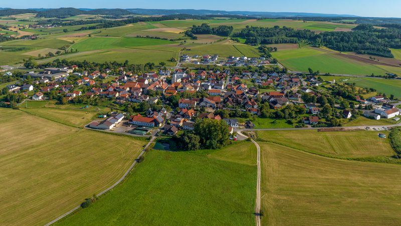 Luftaufnahme eines Dorfes im Coburger Land, umgeben von Feldern und Hügeln